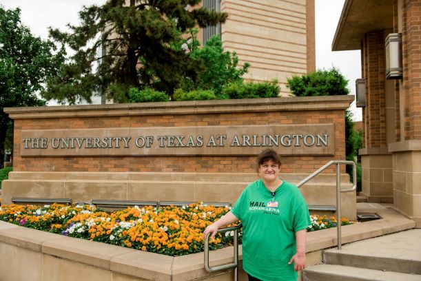 Addy Heaps in front of a University of Texas at Arlington sign