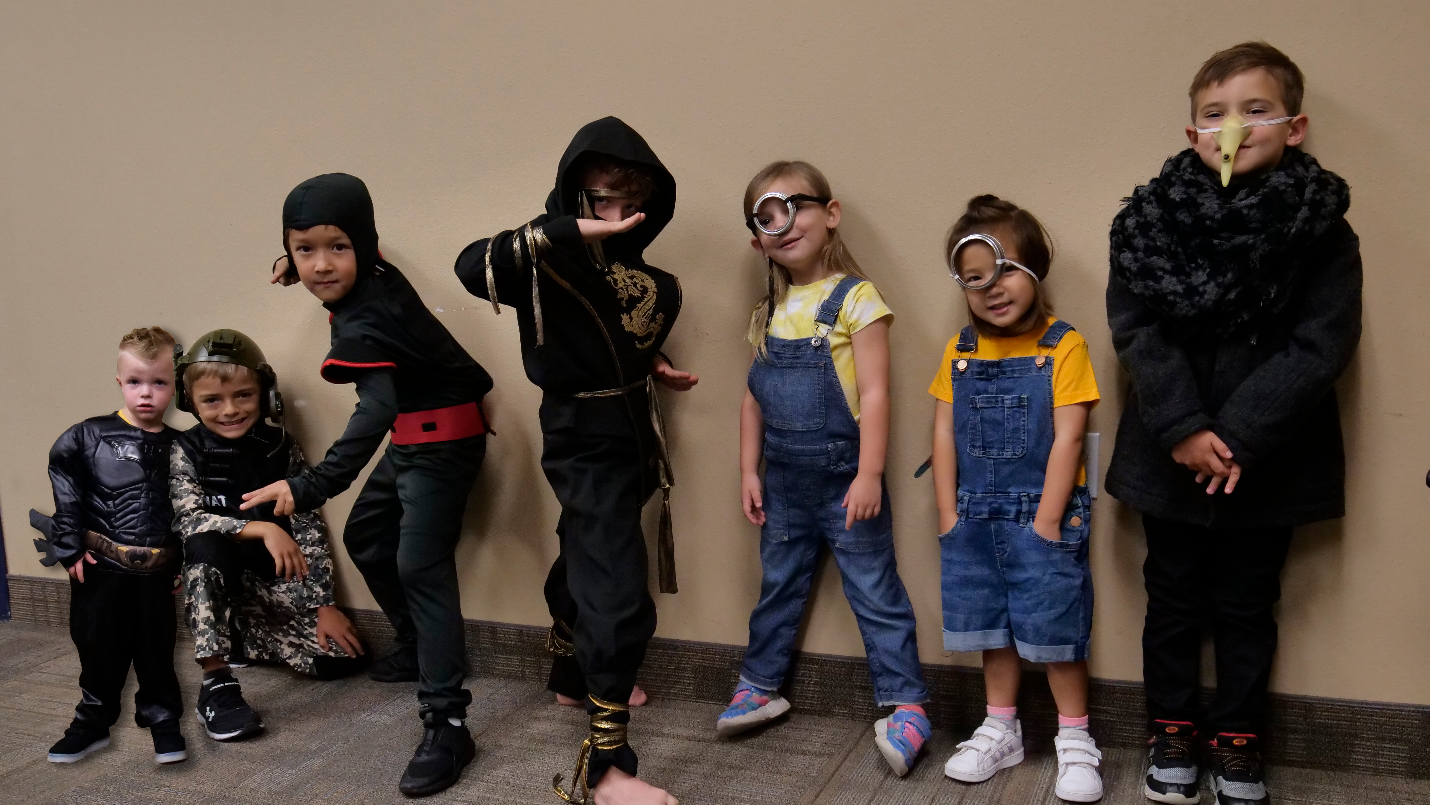 a group halloween costume. from right to left there is a batman, an army man, two ninjas, two minions, and Gru